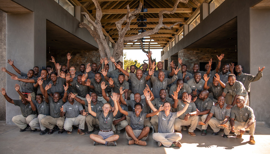 The team at Kapama Private Game Reserve posing together with joyful energy and raised hands, celebrating unity, diversity, and shared passion for wildlife and guest experiences.