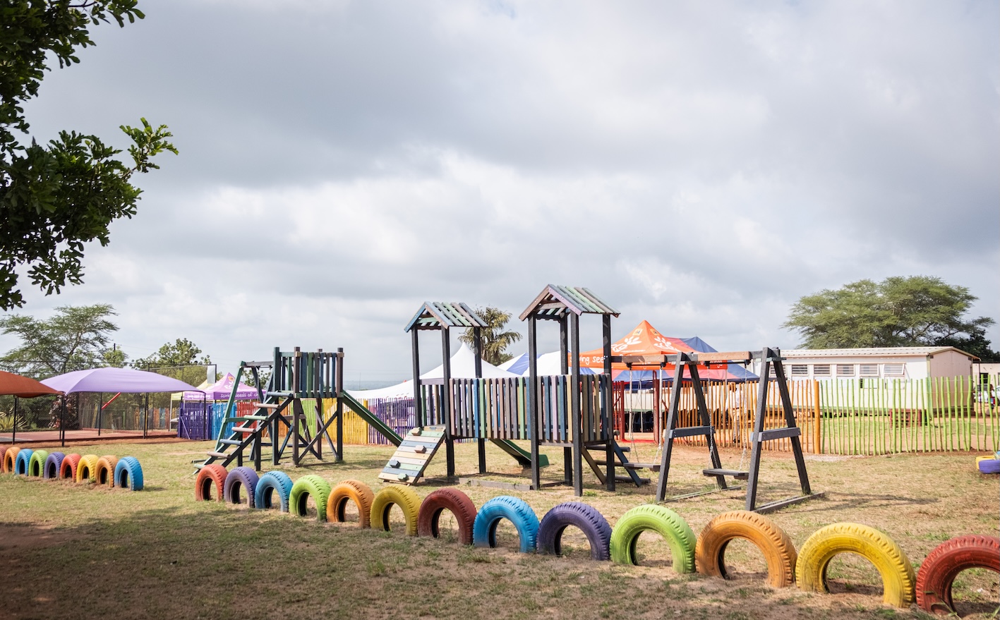 Colorful playground with climbing frames, swings, and painted tires at Makwetse Primary School.