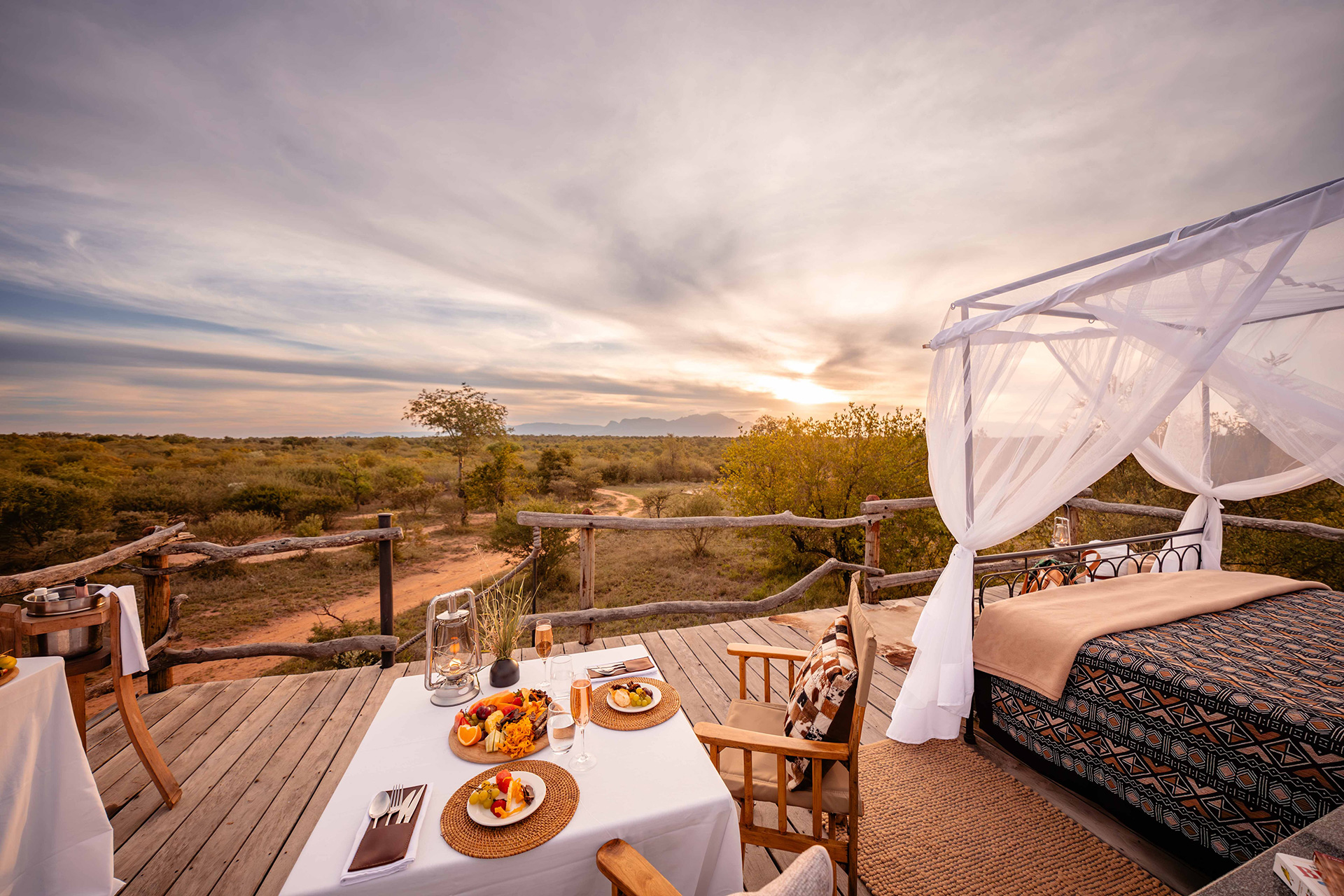 Private romantic sleep-out deck with gourmet dinner and panoramic bush views at sunset in Kapama Game Reserve.